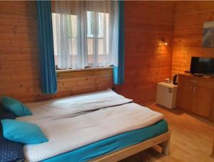 a bedroom with a bed with blue curtains and a television at PanTuszka Pokoje in Pobierowo