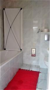 a bathroom with a red rug next to a tub and a sink at Ferienhaus Börstel mit Klimaanlage, Löhne in Löhne