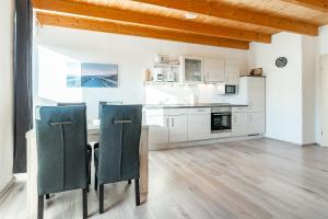 a kitchen with white cabinets and a table and chairs at Ferienwohnung Seepferdchen für 3 Personen am Badesee Tannenhausen in Aurich