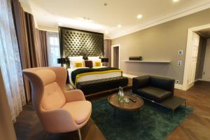 a hotel room with a bed and a couch and chairs at Lumière Boutiquehotel im Fürstenhof Leipzig in Leipzig +33 photos