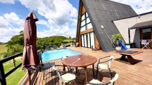 a wooden deck with a table and chairs and a pool at Chalé Paraíso Particular com Piscina Aquecida in Itapetininga