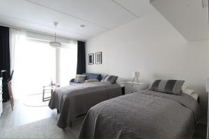 a white room with two beds and a window at Pramea Apartments Majakka in Jyväskylä