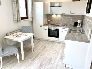 a kitchen with white cabinets and a table and a sink at FeWo Seegras in Grödersby