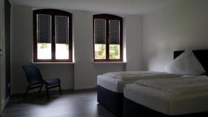 a bedroom with two beds and a chair and windows at Ferienhaus Loreleytraum, Wohnung Erdgeschoss in Sankt Goarshausen