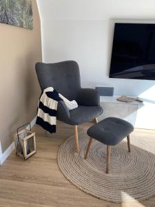 a chair and a stool in a living room at Heimathafen Damp, Haus 9 in Damp