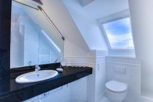 une salle de bain blanche avec un lavabo et une fenêtre dans l'établissement Windeby 1D, à Wenningstedt