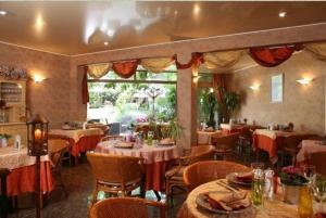 um restaurante com mesas e cadeiras num quarto em Hôtel Beatus em Cambrai