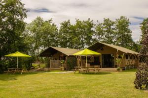 StoutenburgZorgcamping De Ruif De Peppelhoeve的院子内带桌子和遮阳伞的建筑