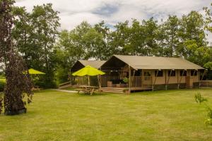StoutenburgZorgcamping De Ruif De Peppelhoeve的一个带桌子和黄色遮阳伞的大型帐篷