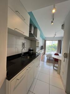 a kitchen with white cabinets and a black counter top at Flat Wise Confort in São Paulo