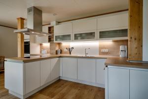 a kitchen with white cabinets and wooden floors at Sandsturm in Prerow