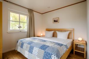 a bedroom with a bed with a blue and white blanket at Sandsturm in Prerow +5 photos