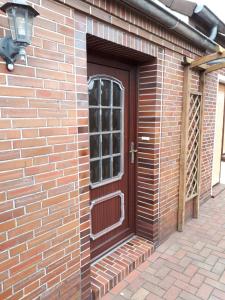 a brick building with a brown door with a window at Günstige Wohnung in Ostfriesland auch für die kleine Familie in Utarp +17 photos