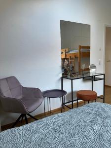 a bedroom with a bed and a chair and a table at Penthouse perfekt für Teams, Familien und Gruppen in Bad Mergentheim +17 photos