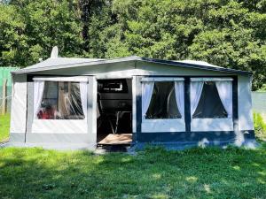 黑灵斯多夫Mietwohnwagen 03的蓝白的帐篷,坐在草地上