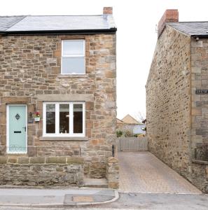 ein Steinhaus mit einem weißen Fenster und einer Ziegelwand in der Unterkunft Rowan Cottage Lanchester-Escape Beyond Holiday Lets in Lanchester