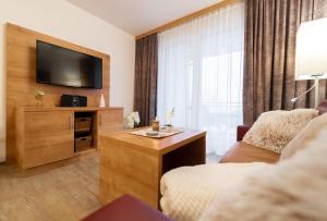 a living room with a television and a couch and a chair at Fewo Feldbergturmblick in Rinken