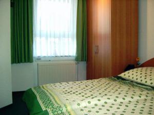a bedroom with a bed and a window with green curtains at de ebb in Dorum-Neufeld