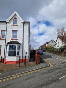 a white house with red windows on a street at 5 Bedroom semi detached home with off road parking in Merthyr Tydfil