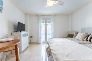 a bedroom with a bed and a table and a tv at MalagaSuite El Levante Apartments in Torremolinos +45 photos