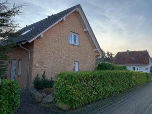 a brick house with a hedge in front of it at Boddenblick 3B in Fuhlendorf