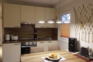a kitchen with white cabinets and a wooden table at Boddenblick 3B in Fuhlendorf +4 photos