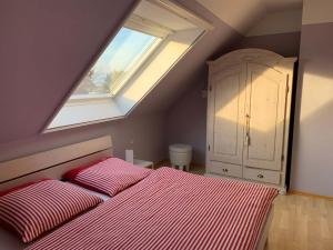a bedroom with a red and white bed and a window at Boddenblick 3B in Fuhlendorf