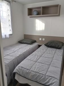 dwa łóżka ustawione obok siebie w pokoju w obiekcie MH 468 LUMINOSA 3ch dont 1 suite parentale et 2sdb proche des activités dans camping 4 étoiles w mieście Saint-Julien-en-Born