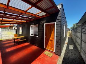 a house with a wooden door and a bench on a porch at Casa Grande en Osorno central en parcela 2 para 6 p in Osorno