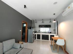 a kitchen and living room with a couch and a table at The Leaf Bankrut - Cosy Cottage in Ban Krut
