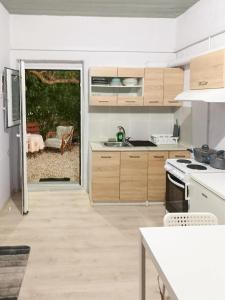 a kitchen with wooden cabinets and a door to a patio at Marina's Garden Nests - Holiday Bliss Getaways in Romanós