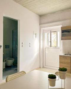 a white room with a table and a bathroom at Marina's Garden Nests - Holiday Bliss Getaways in Romanós