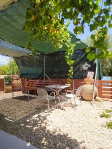 a table and chairs under a green tent at Marina's Garden Nests - Holiday Bliss Getaways in Romanu