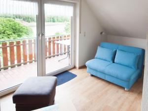 a living room with a blue couch and a balcony at Komfortable Ferienwohnung Mit Seeblick in Bad Arolsen