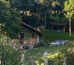 a house with a car parked in front of it at Chalé Bom Jardim in Camanducaia