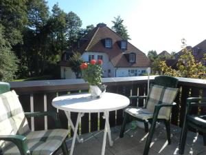 a table and chairs on a balcony with a vase of flowers at Resi M5 in Prerow