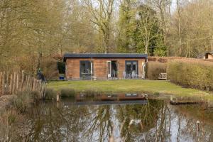 a cabin in the woods next to a pond at NEW Hello Zeeland - Cozy Country Cottage in Wissenkerke