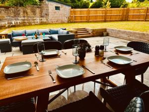 a wooden table with plates and utensils on a patio at Knatchbull Cottage in Downhead