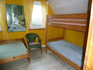 a bedroom with two bunk beds and a chair at Gundi's Ferienhaus in Dorum-Neufeld +5 photos