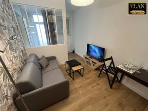 a living room with a couch and a flat screen tv at Le Voltaire in Niort
