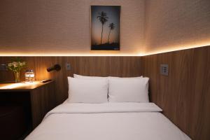 a bedroom with a bed with white sheets and palm trees at W Airport Rooms Fortaleza Hotel dentro do Aeroporto in Fortaleza