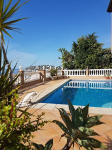 a swimming pool next to a fence and the ocean at Cortijo de la luz App Sol in Almuñécar