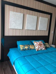 a blue bed with three pictures on the wall at BTS Bearing 23Fl 68sqm condo with open city view Shared rooftop and gym in Samut Prakan