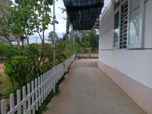 a sidewalk next to a white building with a fence at Homestay Vạn Hưng in Vạn Ninh