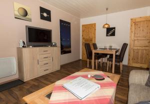 a living room with a tv and a table at Ferienhaus Saturn im Sternenpark in Lochow