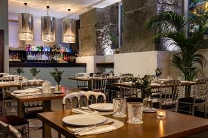 a restaurant with wooden tables and chairs and lights at Hospes Puerta de Alcalá, a Member of Design Hotels in Madrid