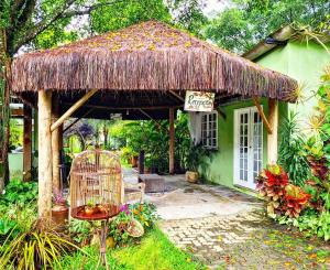 a small green house with a thatch roof at Pousada Art & Flora in Guapimirim
