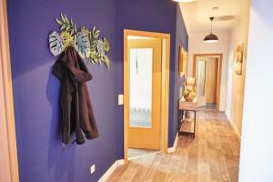 a hallway with a purple wall with coats hanging on it at City-Apartment 1 in Bernburg