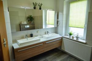 a bathroom with two sinks and a large mirror at City-Apartment 1 in Bernburg