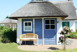 ein blau-weißes Cottage mit einem Strohdach in der Unterkunft Ferienhaus Muschelsucher in Glowe